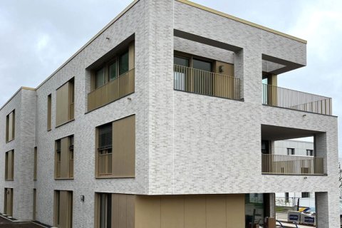 Ausschnitt einer Fassade Gebäudeausschnitt einer Fassade mit hellen Steinen und beigefarbenen Blechverkleidungen, großen Fensterflächen und Loggien